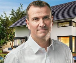 Mann in weißem Hemd vor modernem Haus mit Garten und Pool im Hintergrund.