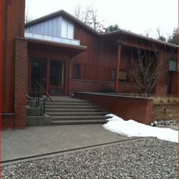 Modern brick building with stairs, snow, and gravel pathway in front.
