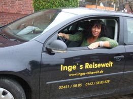 Eine Frau sitzt in einem Auto mit der Aufschrift "Inge's Reisewelt" und einer Telefonnummer.