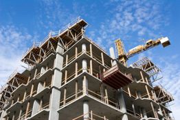Edificio in costruzione con gru, cielo blu sullo sfondo.