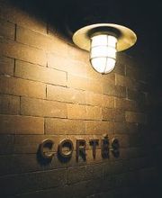 Luz acesa na parede de tijolos com a palavra "Cortés".