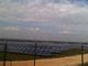 Solaranlage auf einem Feld an einem bewölkten Tag, umgeben von einem Zaun.