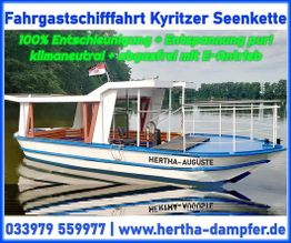 Weiß-blaues Passagierschiff "Hertha-Auguste" auf einem See mit Wald im Hintergrund.