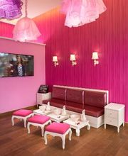 Sala de estar rosa con sofás, TV y mesas pequeñas adornadas con platos y servilletas.