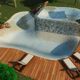 Piscina su due livelli con cascata, circondata da lettini su un patio in legno.
