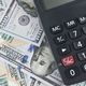 Calculator on U.S. hundred-dollar bills, symbolizing finance and budgeting.