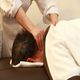 Person receiving a neck massage while lying face down on a massage table.