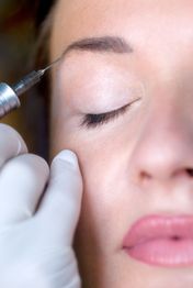 Frau erhält Kosmetikbehandlung mit Injektion im Gesicht. Augen geschlossen, Nahaufnahme.