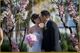 Bride and groom kiss under pink flower archway at wedding.