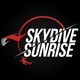 Logo Skydive Sunrise: testo bianco su fondo nero, con un paracadutista e un sole stilizzati.