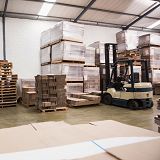 Warehouse interior with stacked pallets and a forklift.