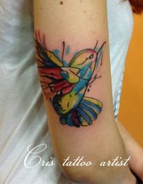Tatuaje de colibrí colorido en el brazo de una persona, estilo acuarela.