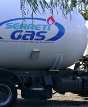 Camion cisterna bianco con logo "Serreti Gas" parcheggiato accanto a un albero.