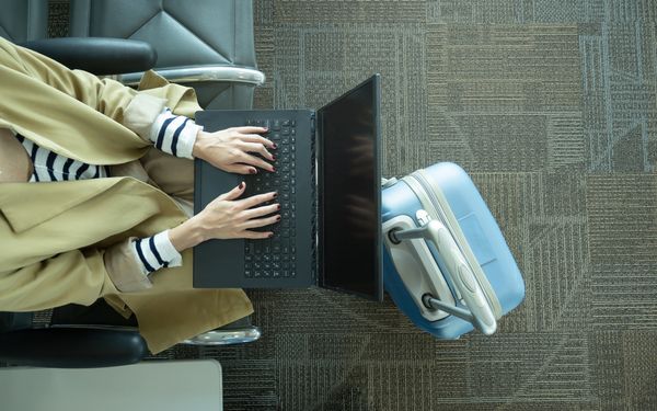 Frau sitzt am Flughafen mit ihrem Laptop