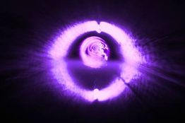 Leuchtender, violetter Wirbel mit symmetrischer Reflexion auf einer Wasseroberfläche.