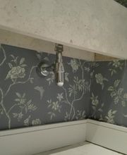 Baño con papel tapiz floral gris y grifo metálico en pared decorada.