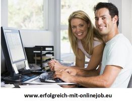 Ein Mann und eine Frau lächeln am Computer in einem Büro.