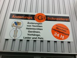 Schild einer Schneiderei mit Änderungs- und Hemdenservice, 24-Stunden Waschen und Handbügeln.