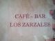 Texto en la pared: "Café - Bar Los Zarzales" en fondo de ladrillos.
