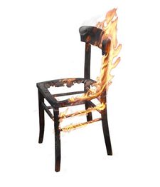 Ein brennender Holzstuhl mit Flammen, der teilweise verbrannt ist und auf einem weißen Hintergrund steht.