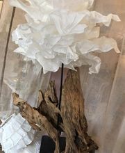 Holzskulptur mit weißen, gewellten Papierblättern, die einer Blume ähneln.