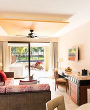 Sala luminosa con sofá rojo, escritorio y terraza con vista al jardín. Decoración moderna.