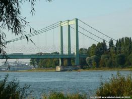 Hängebrücke über einen Fluss mit Bäumen im Hintergrund an einem klaren Tag.
