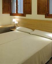 Habitación con dos camas individuales, lámparas de pared y ventanas de madera.