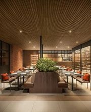Restaurante elegante com mesas dispostas ao redor de plantas, teto de madeira e adega iluminada.