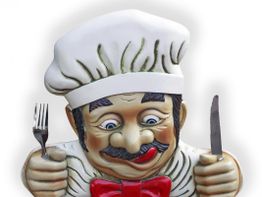 Eine Kochfigur mit Besteck, Kochmütze und roter Fliege leckt sich die Lippen.