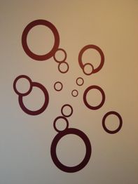 Rote Kreise in verschiedenen Größen auf beigem Hintergrund, kunstvoll angeordnet.