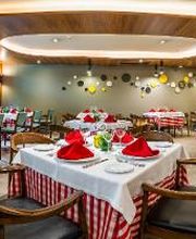 Restaurante elegante con mesas decoradas con servilletas rojas y manteles a rayas rojas y blancas.