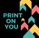 "Tekst 'PRINT ON YOU' met kleurrijke pijlen op een zwarte achtergrond."