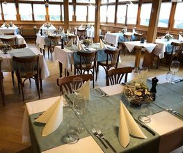 Elegantes Restaurant mit gedeckten Tischen, blauen Tischdecken und gefalteten Servietten.