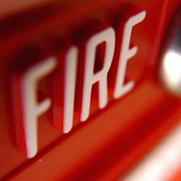 Close-up of a red fire alarm button with the word "FIRE" in white letters.
