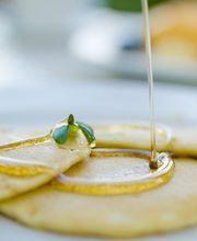 Panqueques con jarabe y frutas: frambuesa, mora y kiwi en un plato blanco.