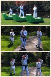 Groep mensen in wit uniform traint karate in een groene parkachtige omgeving.