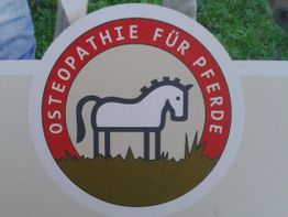 Rundes Logo mit einem weißen Pferd und der Aufschrift "Osteopathie für Pferde" auf rotem Hintergrund.