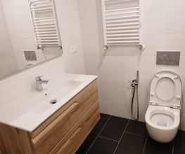 Baño moderno con lavabo, espejo, inodoro y azulejos blancos.