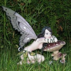 Fantasiefigur mit Schmetterlingsflügeln lehnt sich auf Pilz im Gras.