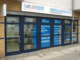 Geschäftsfassade mit blauen Fenstern und Schriftzug für Unfallgutachten und Fahrzeugtechnik.