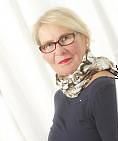 Frau mit Brille und Schal, Blick zur Seite, vor hellem Hintergrund.
