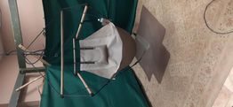A green and beige camping chair suspended by ropes above a patterned floor.