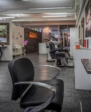 Moderner Friseursalon mit schwarzen Stühlen und großen Spiegeln in einem eleganten Ambiente.