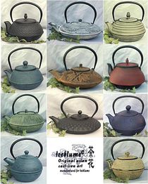 Verschiedene gusseiserne Teekannen in unterschiedlichen Farben und Designs aufgereiht.