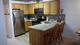 Kitchen with wooden cabinets, granite countertops, and stainless steel appliances. Two bar stools.