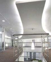 Oficina moderna con pasillo curvo, paredes de cristal y sillas de oficina negras.