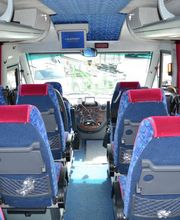 Innenraum eines Reisebusses mit blauen Sitzen und roten Kopfstützen, Blick auf das Cockpit.