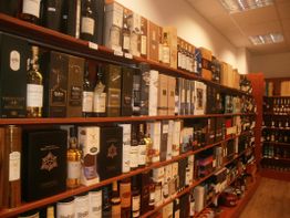 Regale mit verschiedenen Whiskyflaschen und -verpackungen in einem gut beleuchteten Laden.