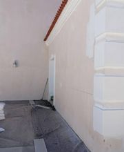 Pared de edificio en reparación, con parches de pintura y materiales de construcción en el suelo.